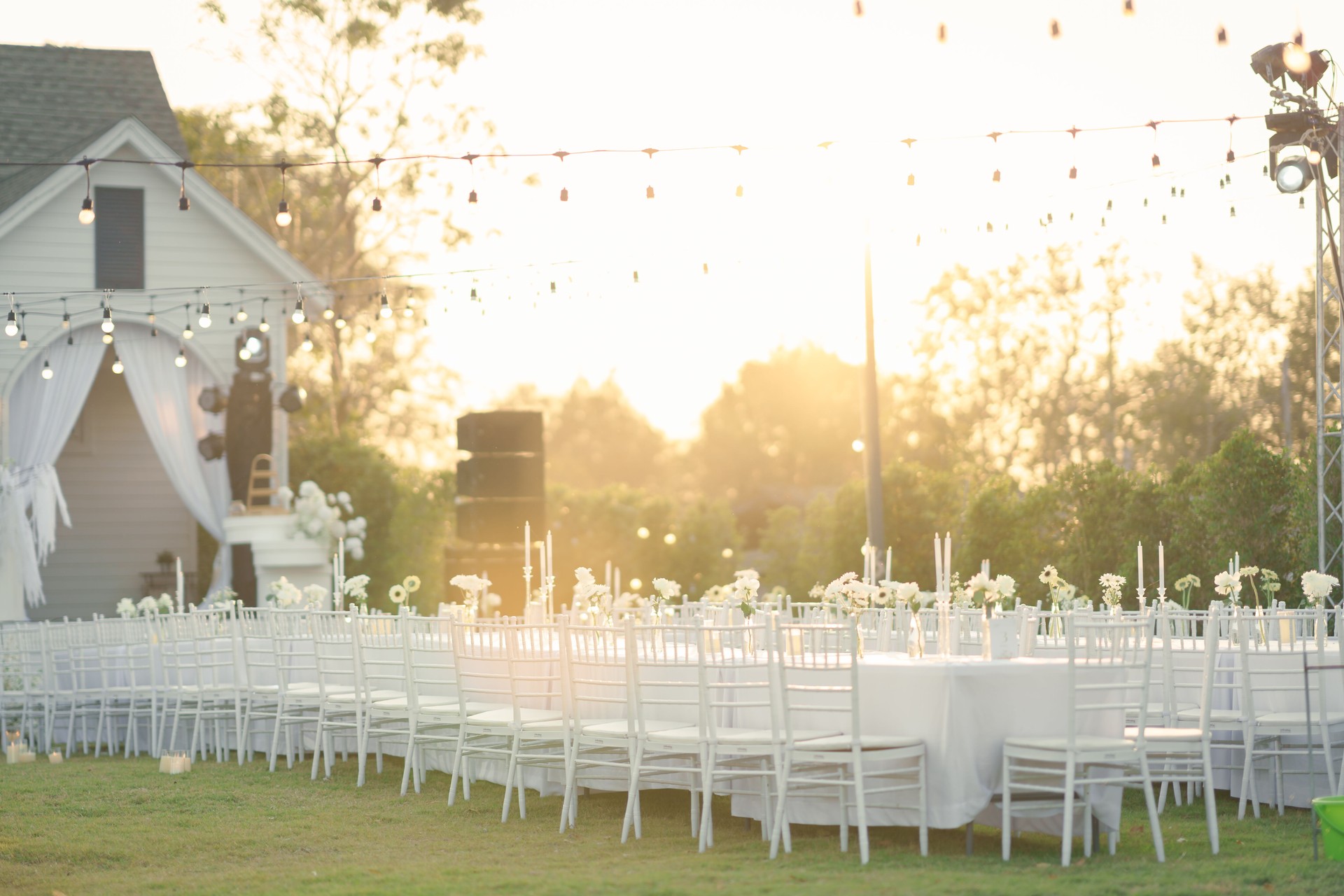 Elegant wedding long table with candle, white rose flower and white chairs in the garden