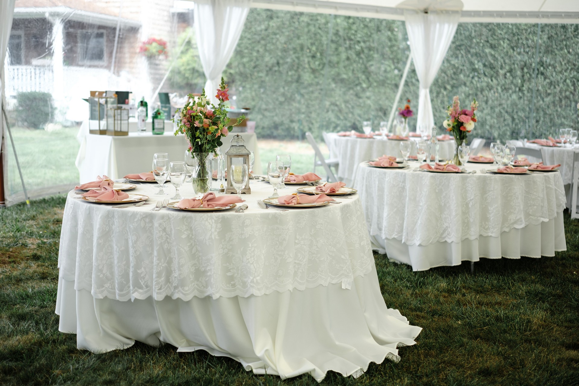 Wedding reception tables under tent with white table cloth and floral centerpiece