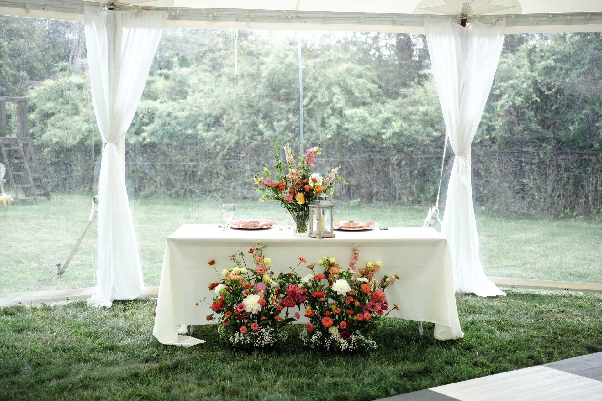 Wedding reception tables under tent with white table cloth and floral centerpiece
