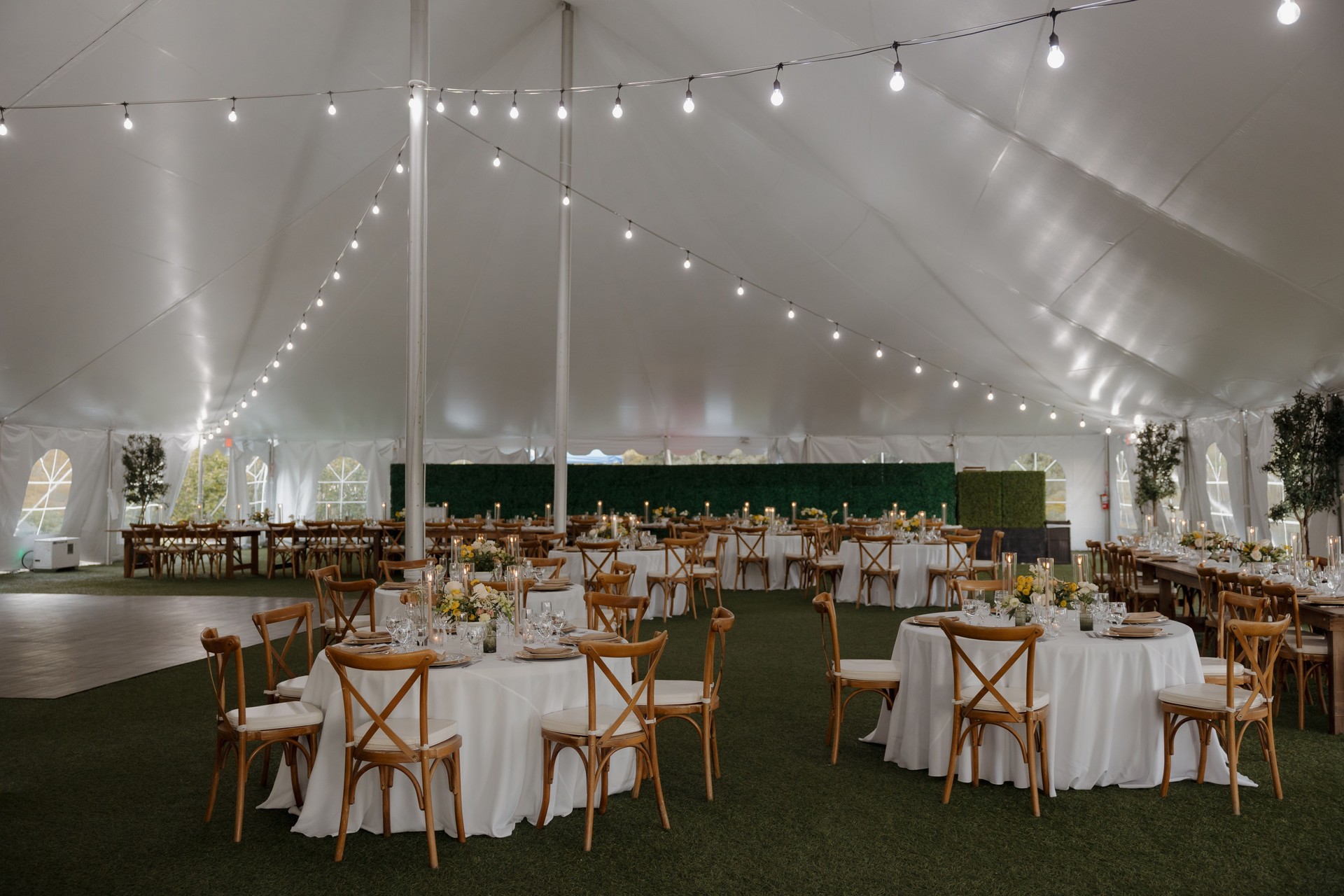 Elegant wedding reception tent with string lights and wooden chairs