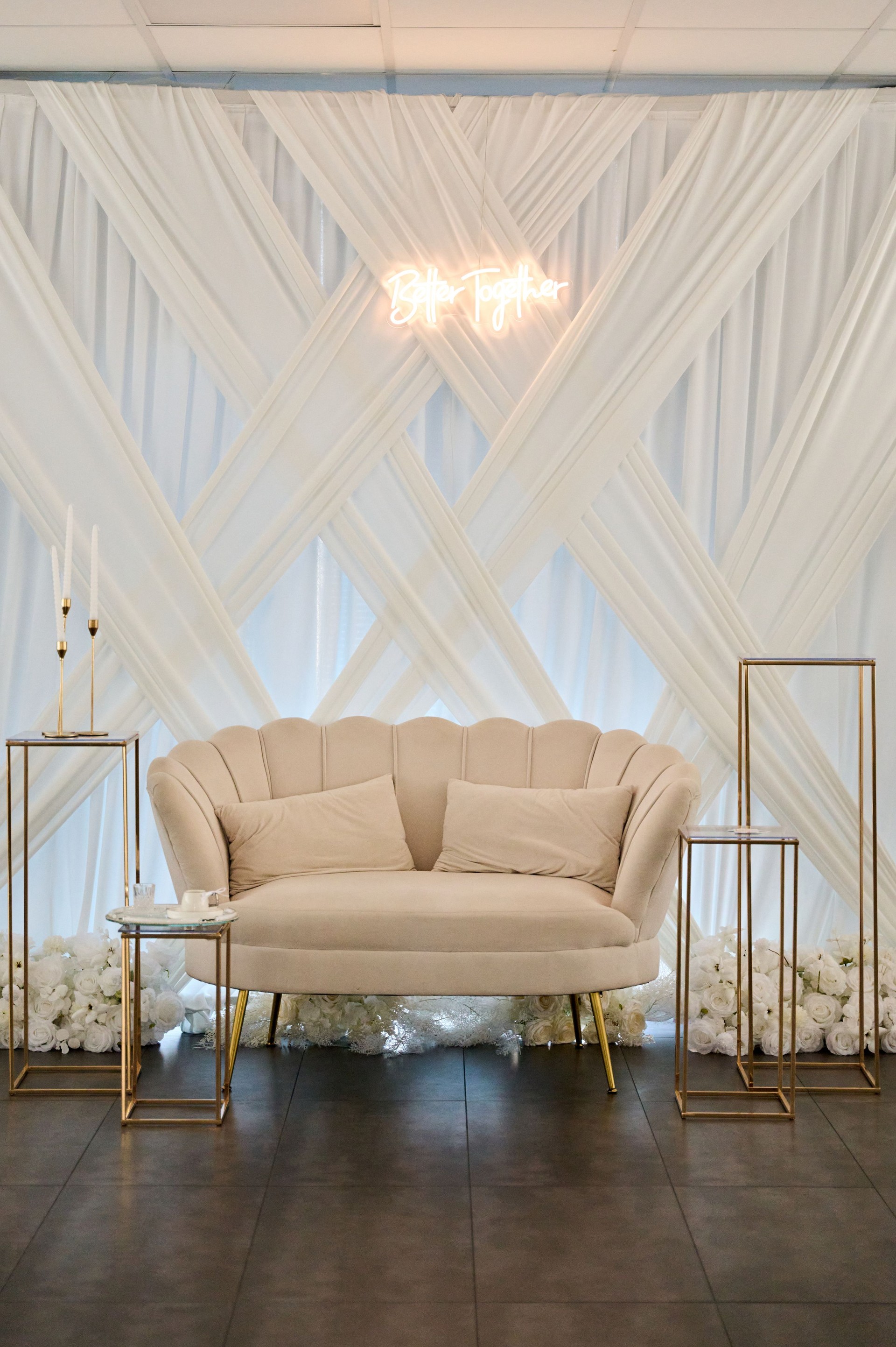 Elegant wedding reception decor featuring crisscrossed drapes and cozy sofa