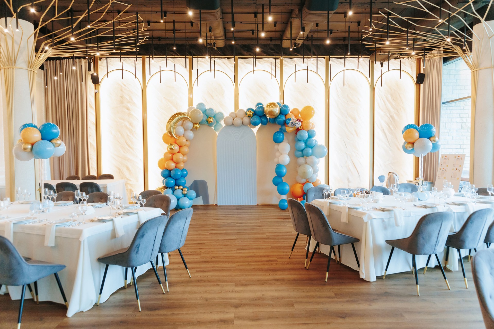Elegant event venue with balloon arch and stylish table arrangements.